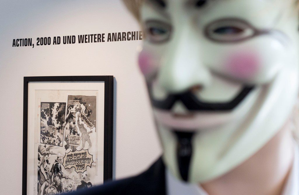 Guy Fawkes-Maske im Vordergrund, eingerahme Comicseite im Hindergrund